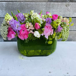 Mixed pink and purple flowers arranged in a green glass vase