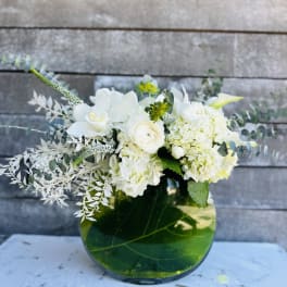 White floral arrangement in a green glass vase