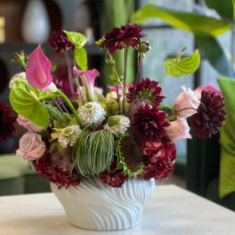 Pink and burgundy floral arrangement in a white vase