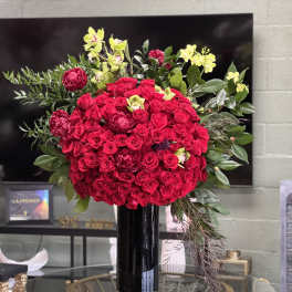 Large bouquet of red roses with yellow orchids in a black vase