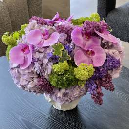 Pink orchids and lavender hydrangeas in a white vase