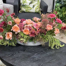 Low floral centerpiece with pink and peach blooms in a shallow white bowl