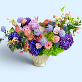 Colorful mixed bouquet in a gold vase with pink, purple, and green blooms