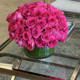 Round bouquet of bright pink roses in a green glass vase