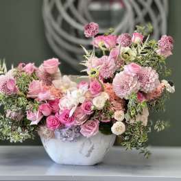Pink floral arrangement in a white bowl vase