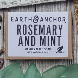 Bar of rosemary and mint handcrafted soap with white label on rustic wood background