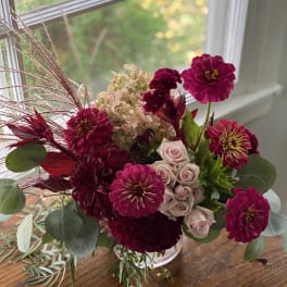 Bouquet of magenta and blush flowers in a clear glass vase
