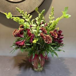 Bouquet of burgundy and yellow flowers in a clear glass vase