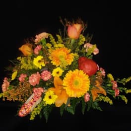 Colorful floral arrangement with yellow and orange blooms and a red apple