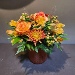 Orange roses and yellow chrysanthemums in a brown vase