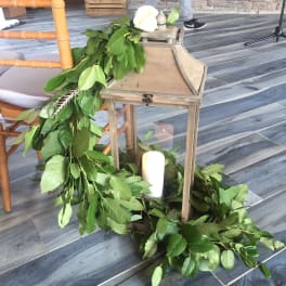 Green garland draped around a wooden lantern with white candles