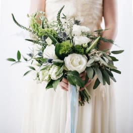 Bride holding a white and green bouquet with ribbon streamers