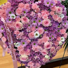 Heart-shaped bouquet of pink and purple flowers with a ribbon