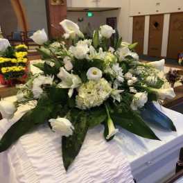 White funeral casket spray with calla lilies and roses