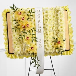 Yellow floral funeral easel spray with a white ribbon reading PSALM 23
