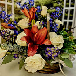 Basket arrangement of white roses, blue flowers, and red lilies