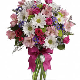Mixed bouquet of pink roses, white daisies, and purple flowers in a glass vase