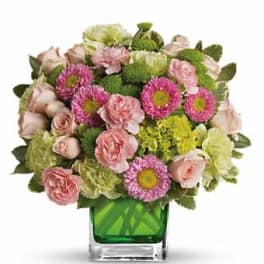 Pink roses and magenta daisies in a green glass vase