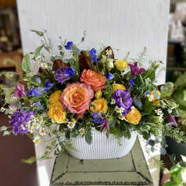 Mixed bouquet of roses, lisianthus, and small daisies in a white vase