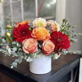 Bouquet of red, peach, and orange flowers in a white vase