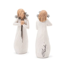 Two angel figurines in white dresses holding small flower stems