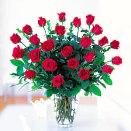 Tall arrangement of long-stem red roses in a clear glass vase