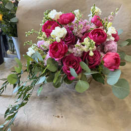 Pink and white bouquet in a clear vase with trailing greenery