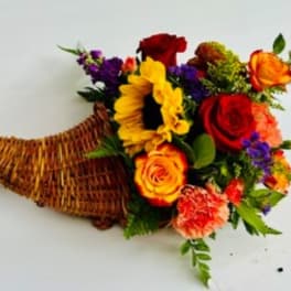 Mixed bouquet with sunflowers, roses, and carnations in a wicker basket