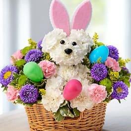 Basket arrangement with a plush bunny and pastel flowers, plus colorful eggs