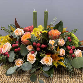 Autumn floral centerpiece with roses, yellow orchid, and two green candles