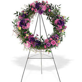 Standing wreath of purple and pink flowers on a metal easel