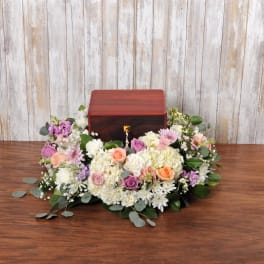 Cremation urn surrounded by a low wreath of white and pastel flowers