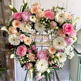 Heart-shaped floral wreath with pink and white flowers on an easel