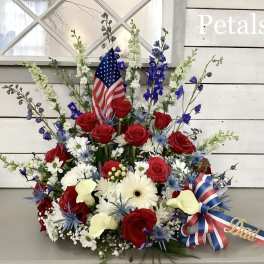 Red roses and white flowers arranged with an American flag and ribbon