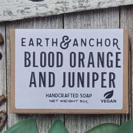 Box of blood orange and juniper handcrafted vegan soap on a rustic wood surface