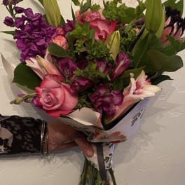 Handheld bouquet of pink and purple flowers with lilies and roses