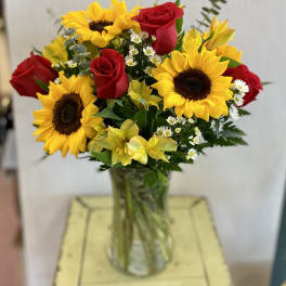 Bouquet of red roses and yellow sunflowers in a glass vase