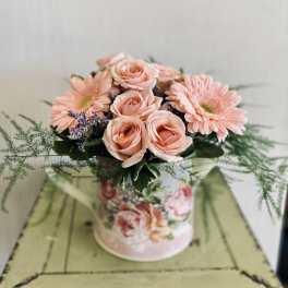 Peach roses and pink daisies in a round floral box