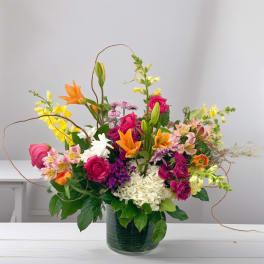 Colorful mixed bouquet in a glass vase with lilies, roses, and hydrangea