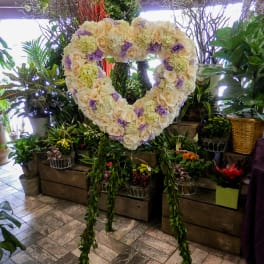 Heart-shaped floral wreath of cream and lavender blooms on a stand