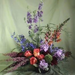 Tall mixed bouquet with orange roses and purple flowers in a black vase