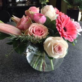 Pink and cream flower arrangement in a glass bowl vase