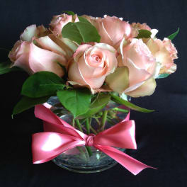 Pink roses in a clear glass vase tied with a pink ribbon