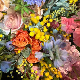 Mixed bouquet with orange and pink roses, blue flowers, and yellow filler blooms