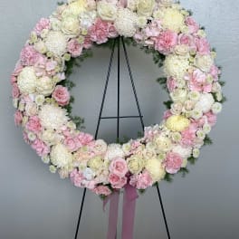 Heart-shaped floral wreath of pink and white flowers on a black stand