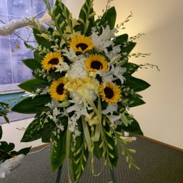 Standing floral spray with sunflowers, white lilies, and yellow blooms