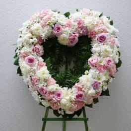 Heart-shaped floral wreath with pink and white flowers on an easel