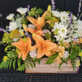 Orange lilies and white daisies arranged in a wooden box