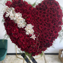Heart-shaped red rose arrangement with white orchids on an easel