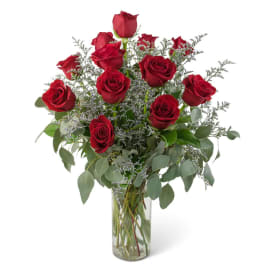 Red roses arranged in a clear glass vase with airy filler and greenery